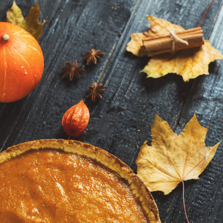 Pumpkin pie on a wooden table with ingredients and decorの写真素材