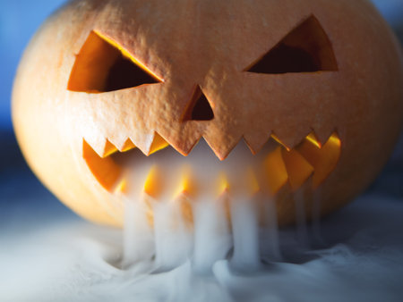Crazy pumpkin monster on Halloween looks through the smoke. Close - up of scary orange pumpkin faceの写真素材