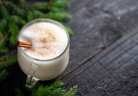 Eggnog winter Christmas drink on the table with cinnamon and spruce branchesの写真素材