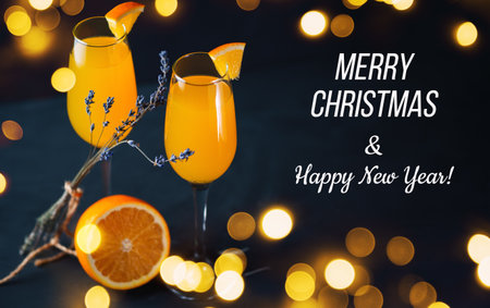 Mimosa cocktail on a dark background with baque garlands, merry Christmas greetings and happy new year textの写真素材