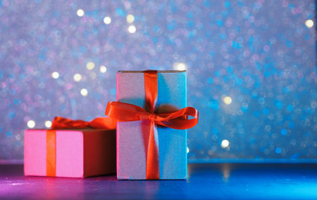 Two gift boxes with a red ribbon on a side neon background. Copy space