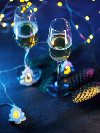 Two glasses of champagne, a Christmas composition. Blue background with a garland in the shape of a Christmas tree. Copy spaceの写真素材