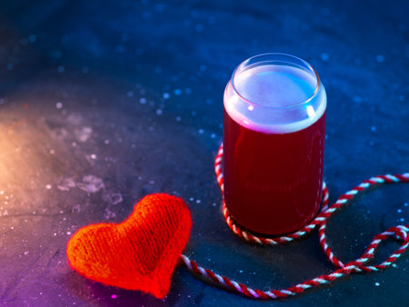 Beer mine valentine. Valentine's day concept. glass of red beer, knitted red heart, blue backlight background, copy spaceの写真素材