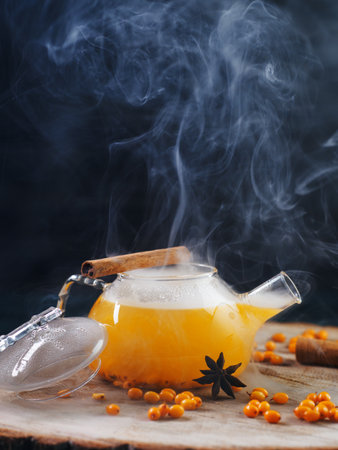 Spicy sea buckthorn tea in a glass teapot. Steam from hot teaの写真素材