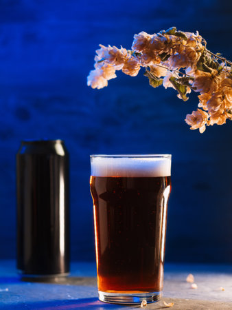Craft light beer glass, beer bottle, dry hops, modern neon illuminated dark backgroundの写真素材