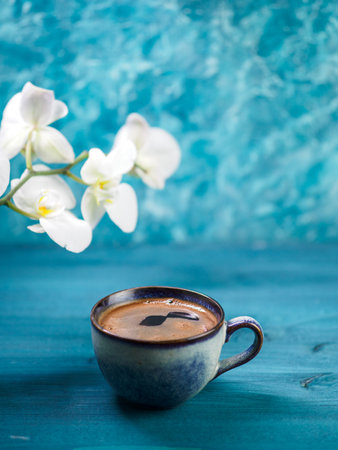 A blue cup of coffee on a blue background. White Orchid Branchの写真素材