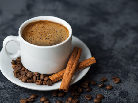 White espresso coffee Cup with cinnamon and coffee beans on dark concrete backgroundの写真素材