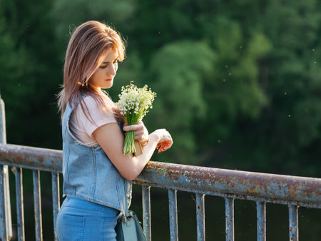 Beautiful girl with a bouquet of flowers at sunset with copyspaceの写真素材