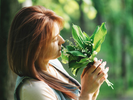 Happy young woman with Lily of the valley bouquet in the Parkの写真素材