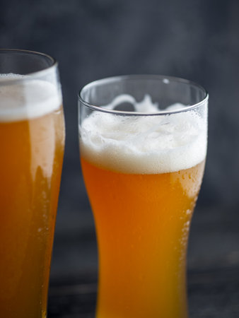Two glasses of unfiltered cold wheat craft beer on a dark tableの写真素材