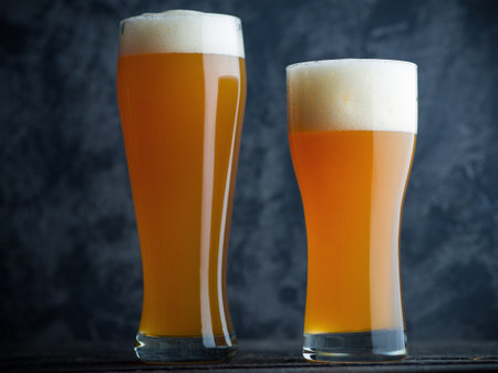 Two glasses of unfiltered cold wheat craft beer on a dark tableの写真素材