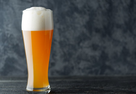 A glass of wheat unfiltered beer on a dark background with copyspaceの写真素材