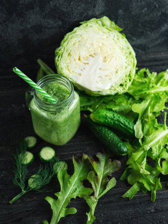 Close-up of green smoothie in a glass jar with ingredients on a dark wooden tableの写真素材
