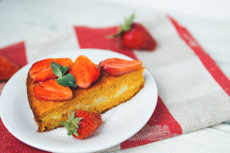 very tasty carrot cake decorated with strawberries on a white tableの写真素材