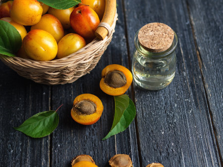 Glass bottle with apricot oil and fresh juicy apricots on the tableの写真素材
