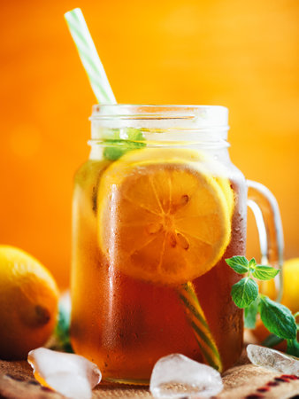 Summer cold black tea with lemon and mint in a jar on a wooden table