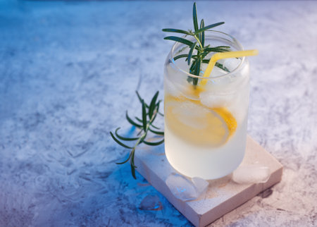 cocktail gin and tonic with lemon and rosemary, stylish color lighting. refreshing cold tonic with iceの写真素材