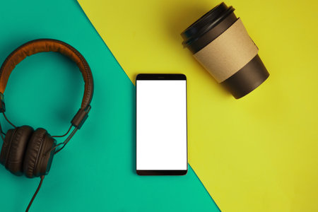 Smartphone, headphones and paper Cup with coffee on bright color background with copyspaceの写真素材