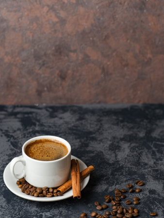 White espresso coffee Cup with cinnamon and coffee beans on dark concrete backgroundの写真素材