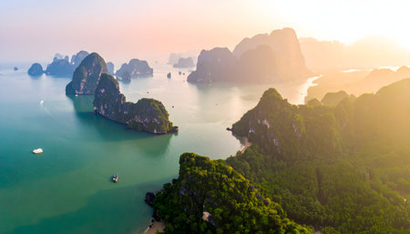 Aerial view of a secluded bay surrounded by jungle-covered rock formations in Southeast Asia, with a vibrant orange sky and turquoise seaの素材