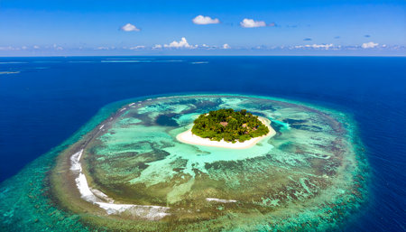 Drone shot of a remote atoll in the deep blue ocean, showcasing the shallow, vibrant ring of the healthy, extensive barrier reef.の素材