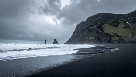 Stormy seascape with dark clouds over a black volcanic sand beach, dramatic rock formations, and strong, foamy surf along the shoreの素材