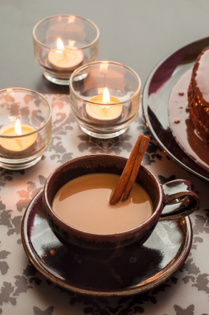 Cup of hot coffee and cinnamon with candlelight on the table の写真素材