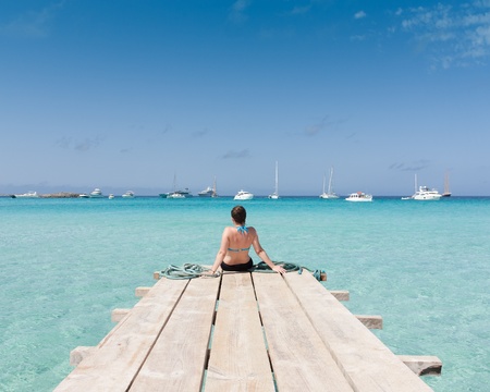 Woman watching the sea sitting on a jettyの写真素材