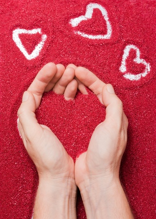 Hands offering a red sand heartの写真素材