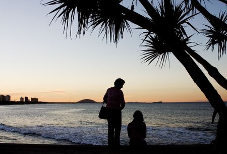 Silhouette of mother and daughter having a conversation at the beachの写真素材