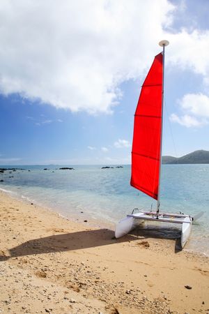 Red sailing boat arrived on a beachの写真素材