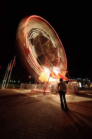 Spinning Ferris wheel watched by Asian woman during festival in Queensland, Australia