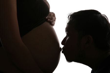Silhouette of a husband kisses her pregnant wife on her belly\rの写真素材