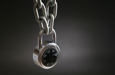 A combination lock an a silver chain over gray backgroundの写真素材