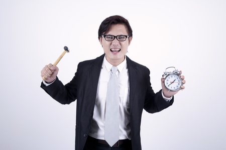 Asian businessman angry with hummer and alarm clock isolated on white