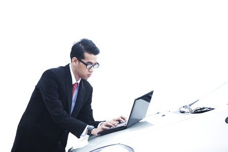 Businessman working with laptop in front of a car