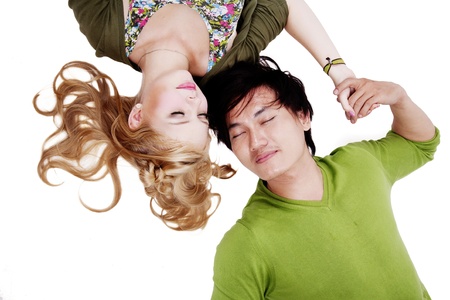 Couple lying on white background while holding their handの写真素材