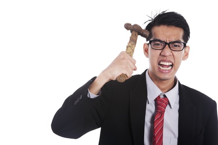 Frustrated businessman hitting his head with hammer on white backgroundの写真素材