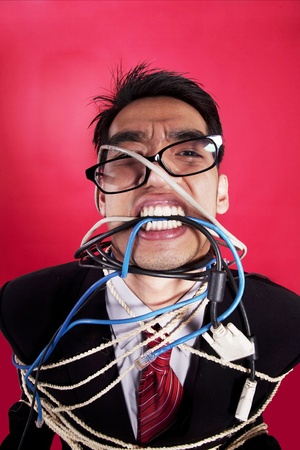 Mad businessman with cables and rope on red backgroundの写真素材
