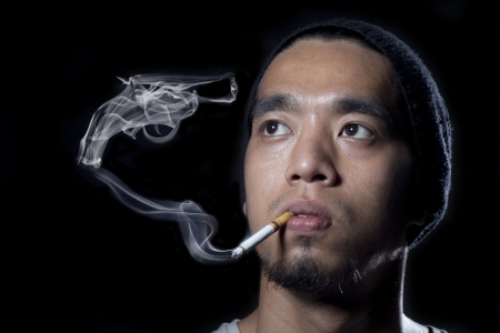 Man smoking with a pistol made of smokeの写真素材