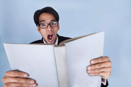 Shocked businessman reading a bookの写真素材