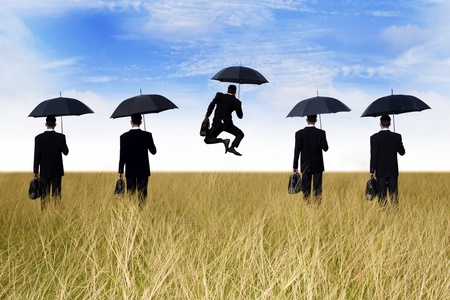 Business success: businessman jumping in front of his teamの写真素材