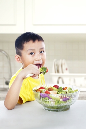 Young asian child eating a big portion of salad. shot in the kitchen roomの写真素材