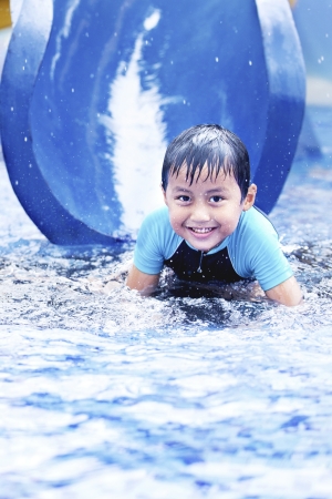 Happy asian boy having fun with water slide during summerの写真素材