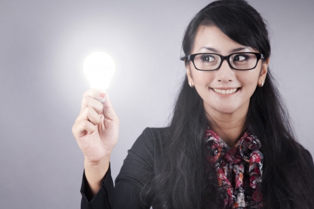 Beautiful Asian Businesswoman with glasses holds a light bulbの写真素材