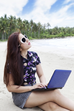 Young casual businesswoman using laptop computer at the beachの写真素材