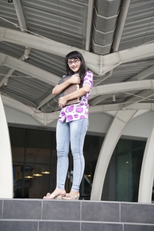Portrait of casual female college student standing in front of campus buildingの写真素材