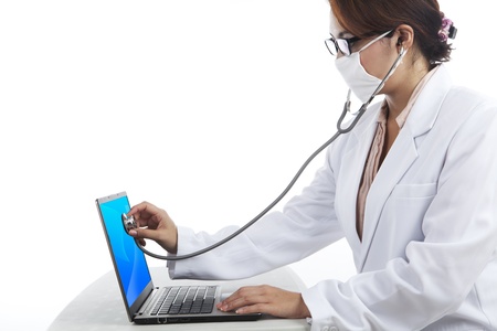 Shot of young woman in lab coat  checking laptop with stethoscopeの写真素材
