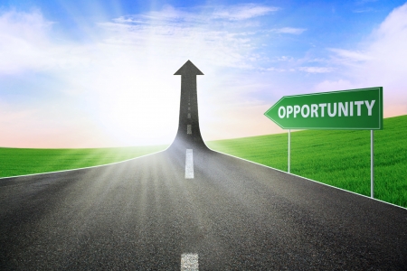 A road turning into an arrow rising upward with a road sign of opportunity, symbolizing the way to gain opportunityの写真素材