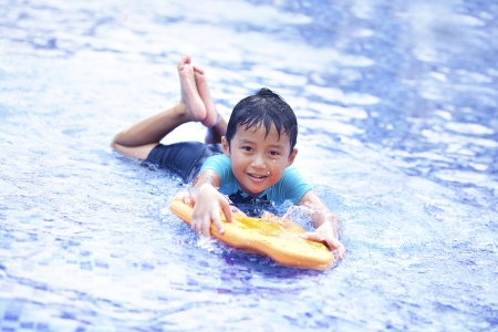 Asian kid having a fun time at swimming pool. Shot during summerの写真素材